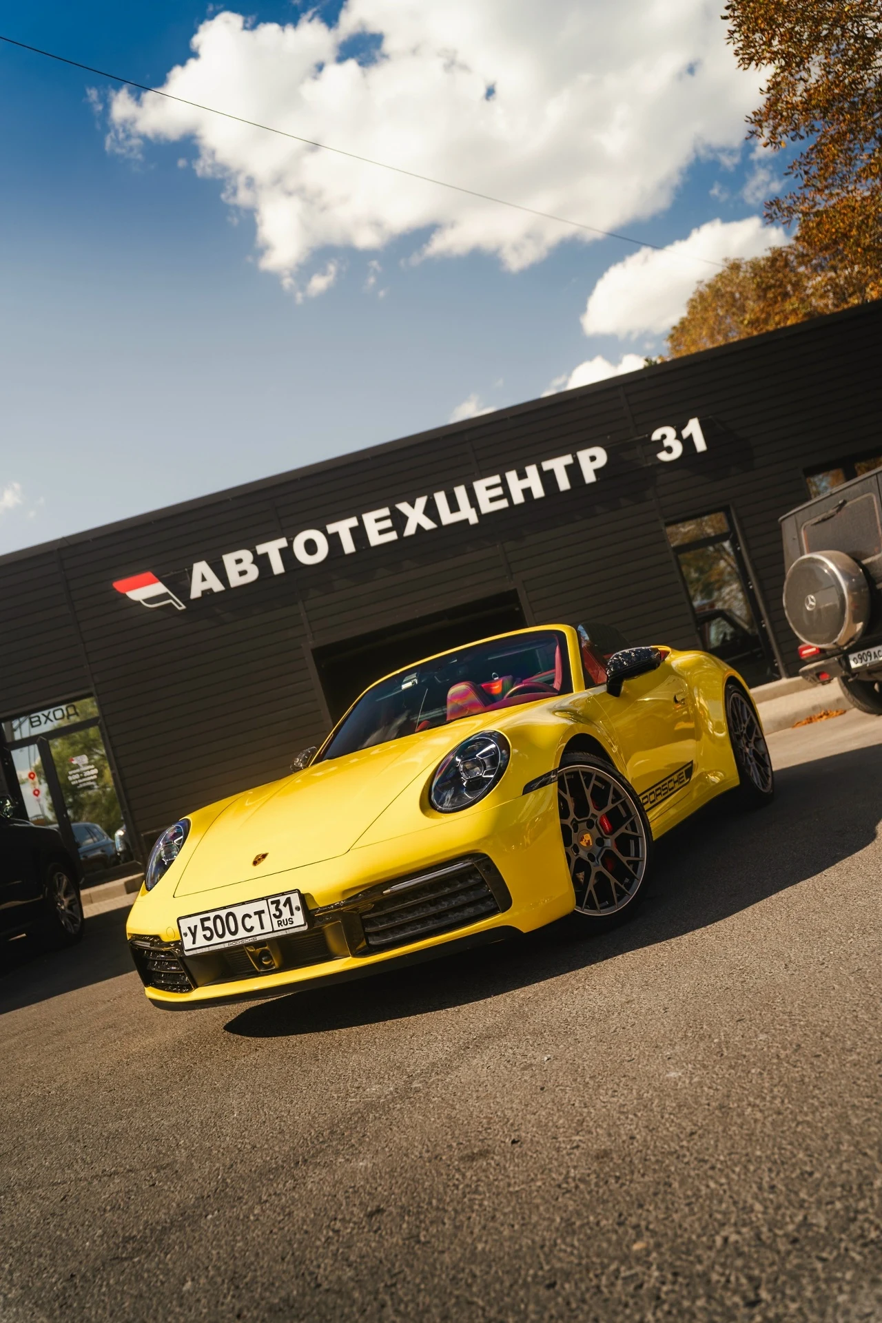Жёлтый Porsche 911 Carrera с карбоновыми элементами у автомобильного центра